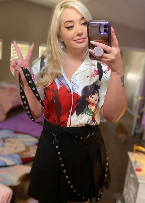 Blonde woman models for selfie while wearing anime shirt.