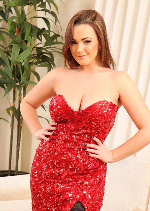 Brunette woman with hands on hips wears sequinned red dress.